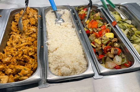 Trays of chicken, rice, and vegetables in the cafeteria